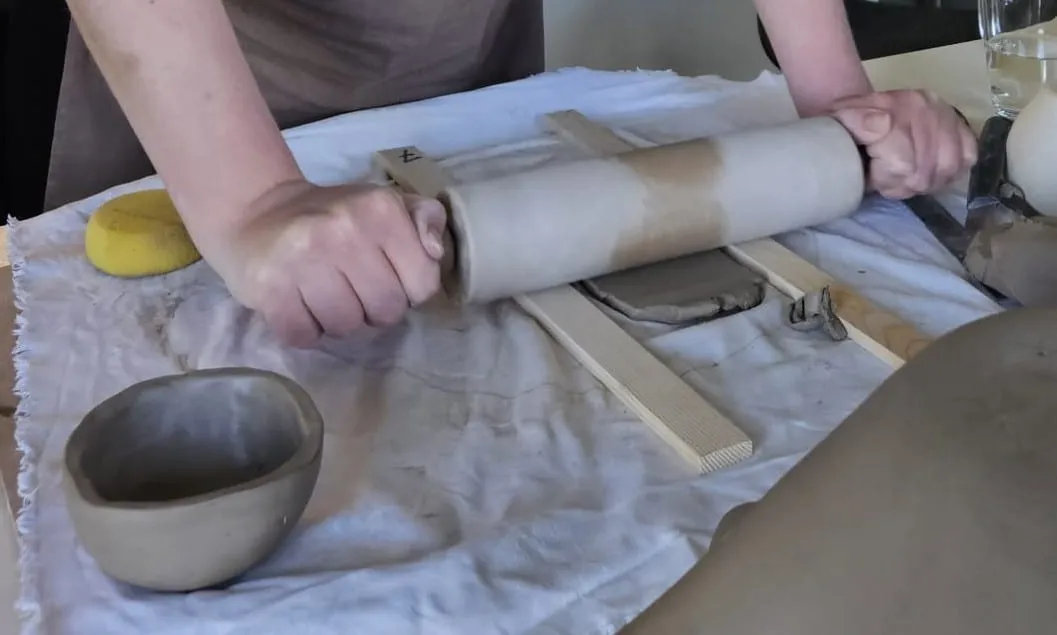 Klei wordt met een deegroller uitgerold in het atelier